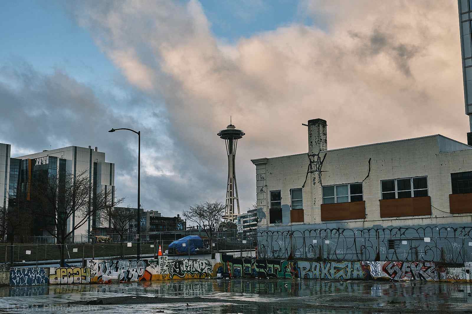 The Seattle Space Needle seen across a littered , graffitied vacant lot