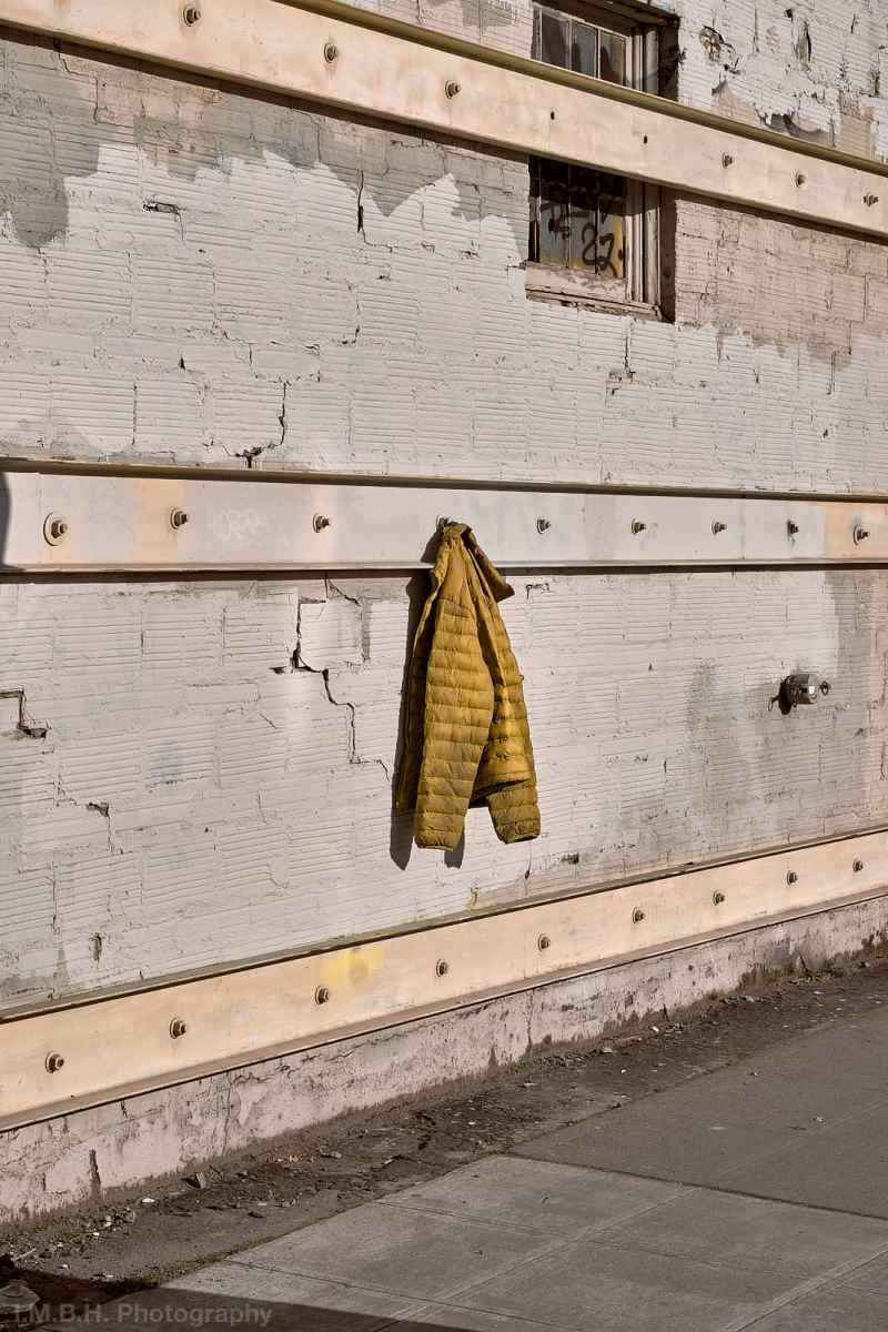 Yellow puffy jacket hanging on an industrial wall