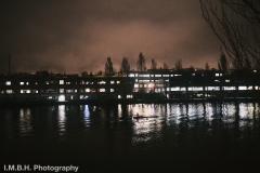 A rowers rows through the reflected light from office windows in the early morning dark